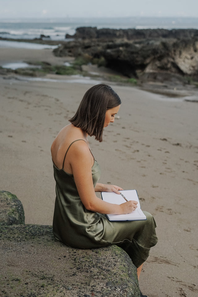 Girl writing in a journal on the beach